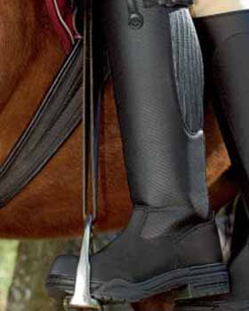 Horse riding boot with stirrup and saddle in the background.